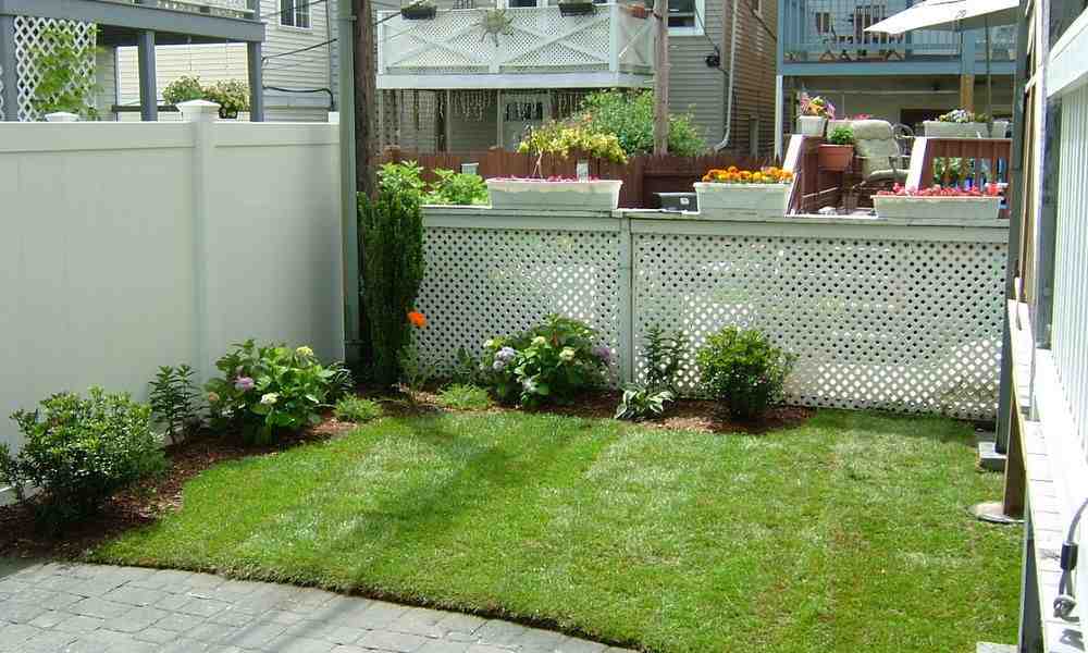 Residential backyard with freshly installed mulch edging, green lawn, and decorative plants, emphasizing expert landscaping services by Boston Landscape Co. for a private oasis.
